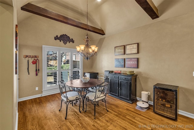 dining space with an inviting chandelier, lofted ceiling with beams, baseboards, and wood finished floors