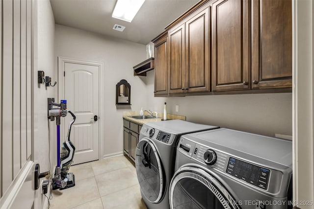 laundry room featuring light tile patterned floors, a sink, cabinet space, washing machine and clothes dryer, and visible vents