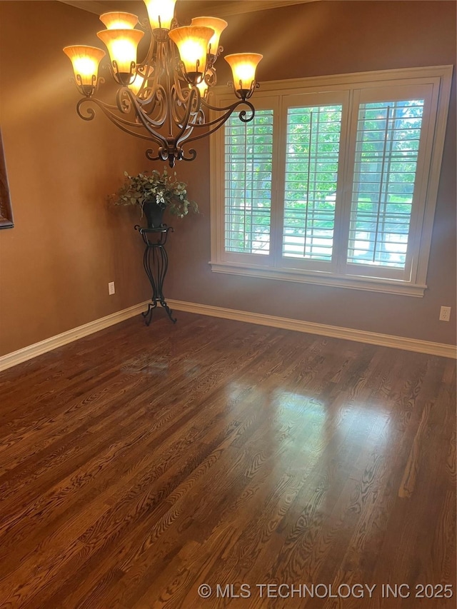 empty room with an inviting chandelier, dark wood finished floors, and baseboards