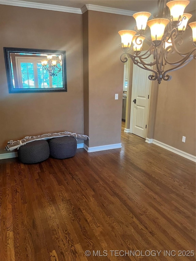 empty room featuring a chandelier, ornamental molding, dark wood-style flooring, and baseboards