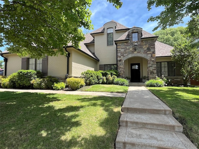 french country style house with stone siding, stucco siding, and a front yard