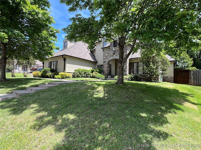 view of front of property featuring fence, stucco siding, stone siding, and a front yard