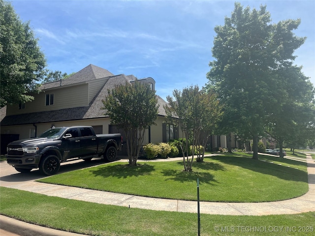 view of side of property featuring a lawn, an attached garage, and concrete driveway