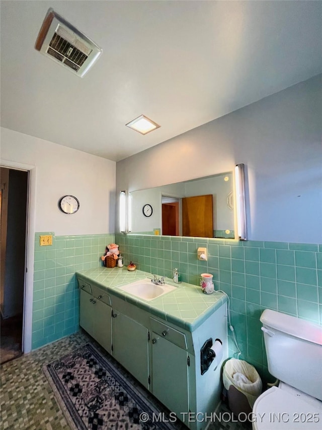 306 N Cherokee St, Beggs, OK 74421 - bathroom with visible vents, toilet, vanity, wainscoting, and tile walls