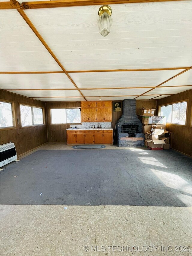 306 N Cherokee St, Beggs, OK 74421 - unfurnished living room featuring a wealth of natural light, heating unit, wood walls, and a wood stove