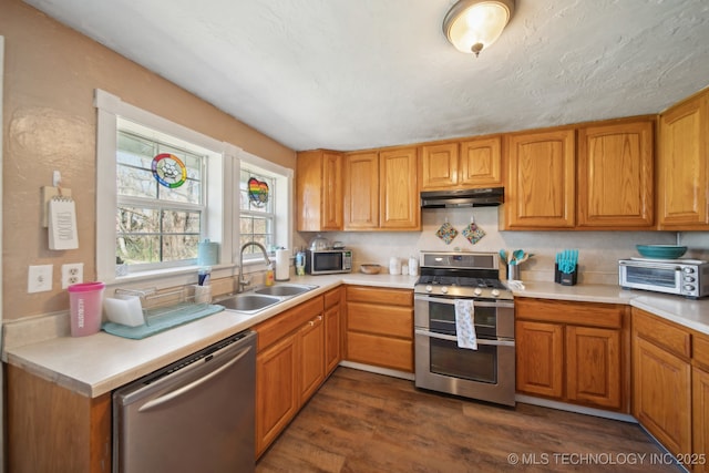 302 W 4th St, Skiatook, OK 74070 - kitchen with under cabinet range hood, stainless steel appliances, light countertops, and a sink