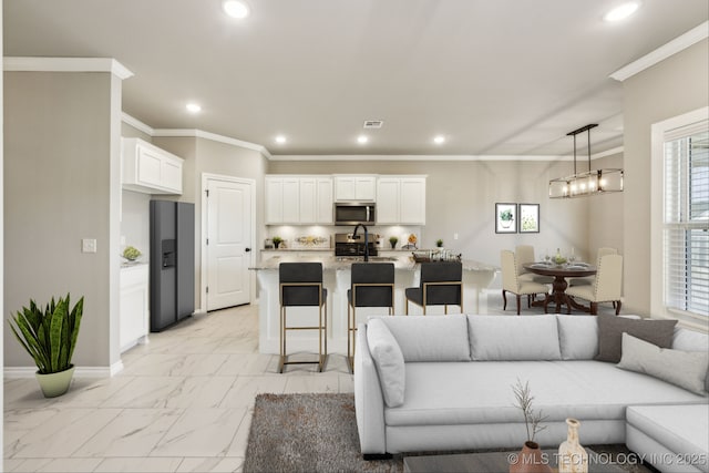 living area featuring a healthy amount of sunlight, recessed lighting, crown molding, marble finish floor, and a chandelier