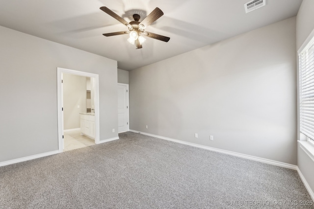 unfurnished bedroom featuring a ceiling fan, baseboards, visible vents, light carpet, and connected bathroom