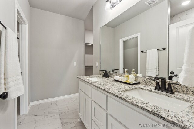 bathroom featuring a sink, visible vents, baseboards, and marble finish floor