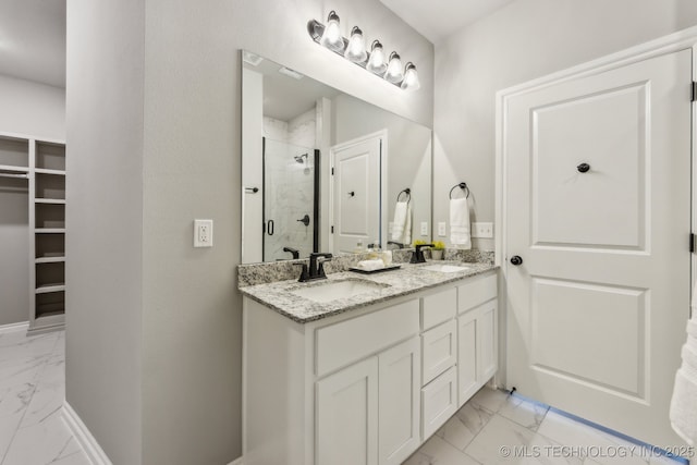 bathroom featuring marble finish floor, a stall shower, a sink, double vanity, and a spacious closet