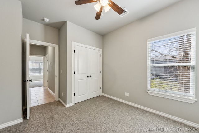 unfurnished bedroom with multiple windows, carpet, visible vents, and a closet