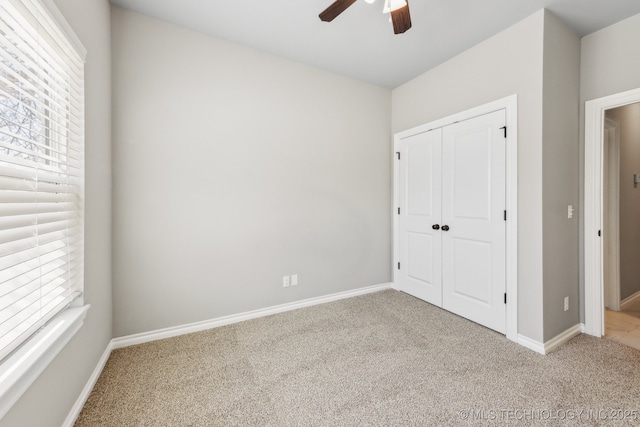unfurnished bedroom featuring a closet, multiple windows, baseboards, and carpet floors