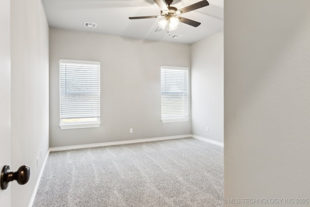 spare room featuring a wealth of natural light, visible vents, ceiling fan, and carpet floors