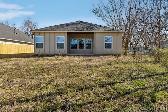 back of property featuring board and batten siding, fence, a lawn, and roof with shingles