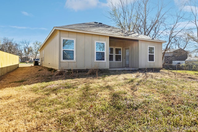 back of property with board and batten siding, a yard, and fence
