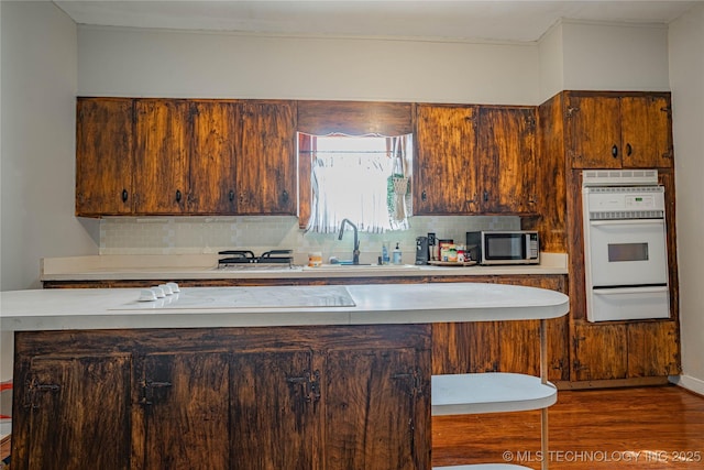 kitchen with oven, a warming drawer, stainless steel microwave, backsplash, and light countertops