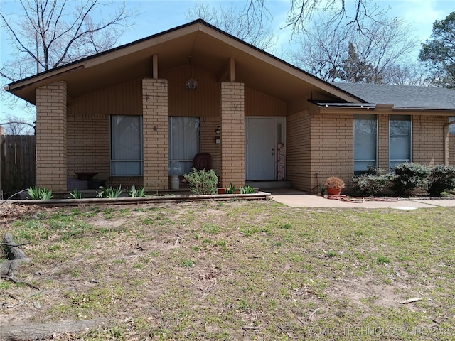 single story home featuring brick siding, a front yard, and fence