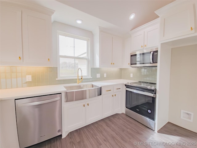 kitchen with a sink, light wood-style floors, white cabinetry, and stainless steel appliances
