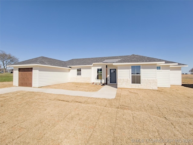 view of front of home featuring an attached garage, driveway, and roof with shingles