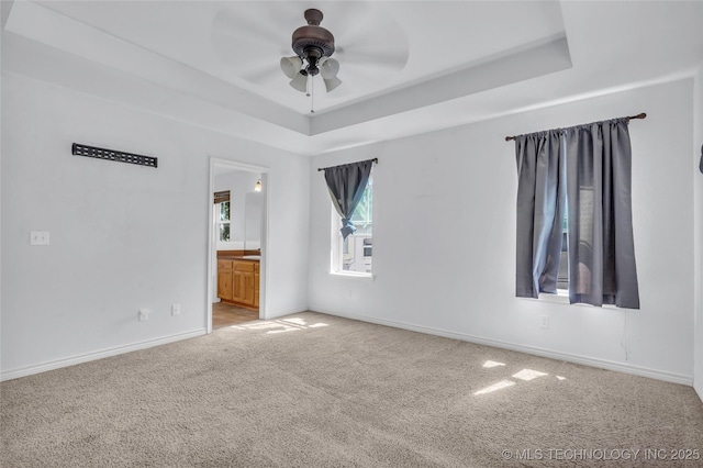 922 Oak Ridge St, Ardmore, OK 73401 - spare room with carpet floors, a ceiling fan, a tray ceiling, and baseboards