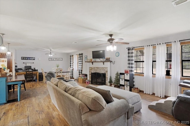 420722 E 1920th Rd, Antlers, OK 74523 - living area featuring light wood finished floors, visible vents, a fireplace, and ceiling fan