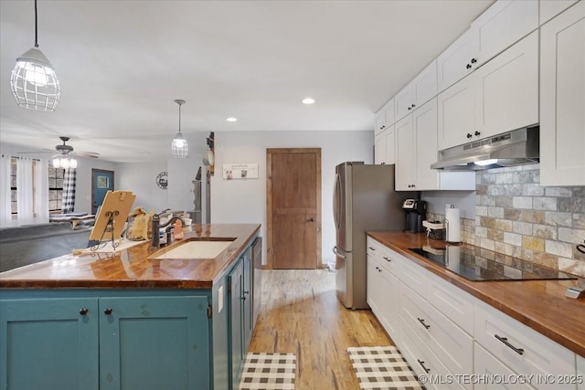 420722 E 1920th Rd, Antlers, OK 74523 - kitchen featuring black electric stovetop, under cabinet range hood, butcher block countertops, blue cabinets, and a sink