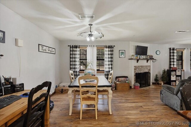 420722 E 1920th Rd, Antlers, OK 74523 - dining space featuring visible vents, a notable chandelier, a brick fireplace, and wood finished floors
