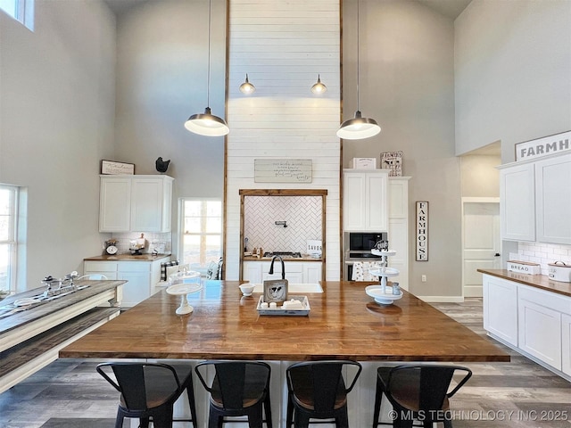 11457 N 510th Rd, Tahlequah, OK 74464 - kitchen with a high ceiling, wooden counters, stainless steel appliances, decorative backsplash, and white cabinets
