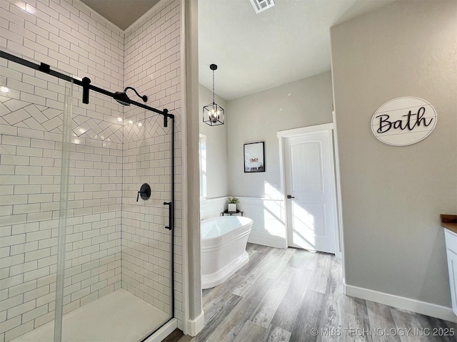 11457 N 510th Rd, Tahlequah, OK 74464 - bathroom with a shower stall, a freestanding bath, wood finished floors, and a wainscoted wall