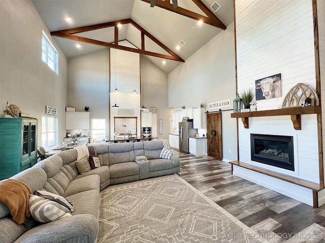 11457 N 510th Rd, Tahlequah, OK 74464 - living area featuring high vaulted ceiling, dark wood-style flooring, beamed ceiling, a large fireplace, and a barn door