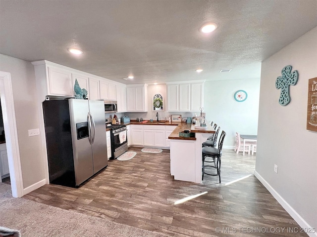 11457 N 510th Rd, Tahlequah, OK 74464 - kitchen with stainless steel appliances, a peninsula, white cabinetry, a sink, and a breakfast bar area