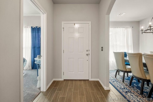 entrance foyer with arched walkways, dark wood finished floors, visible vents, and baseboards