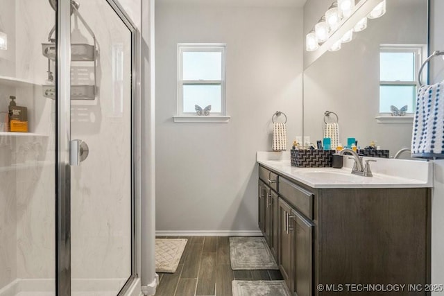 bathroom featuring plenty of natural light, vanity, wood finish floors, and a shower stall