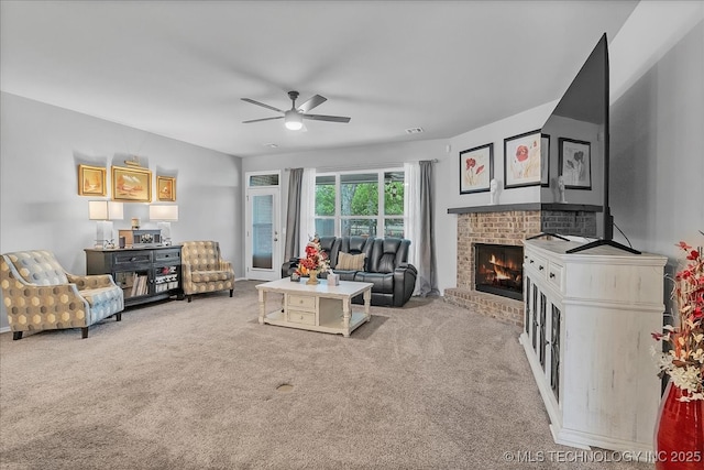 carpeted living area with visible vents, a ceiling fan, and a brick fireplace
