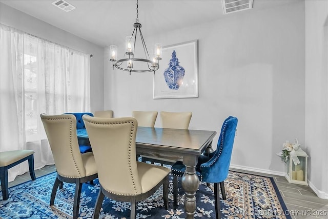 dining space with baseboards, wood finished floors, visible vents, and an inviting chandelier
