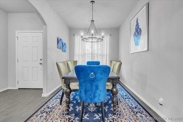 dining space with wood finished floors, visible vents, arched walkways, baseboards, and a chandelier