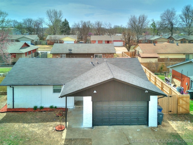 view of front of property with fence, roof with shingles, a residential view, a garage, and brick siding