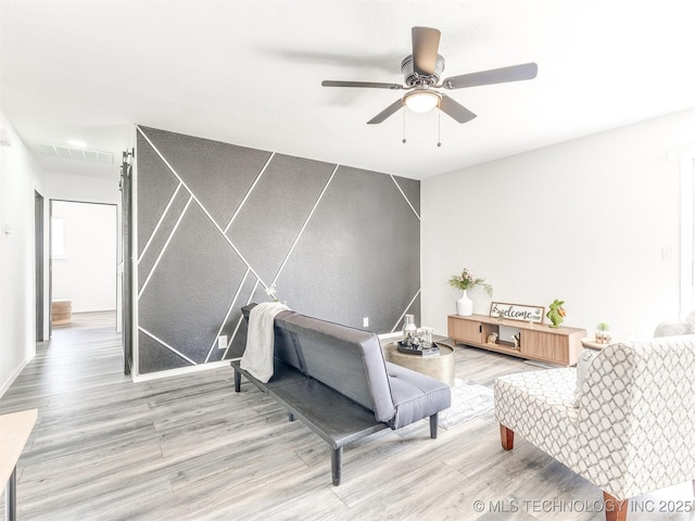 living room with visible vents, a ceiling fan, and wood finished floors