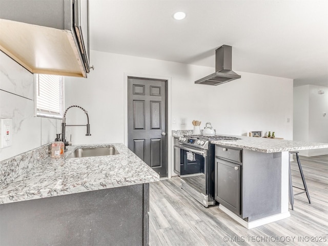 kitchen with range hood, a peninsula, a sink, a kitchen breakfast bar, and stainless steel gas stove