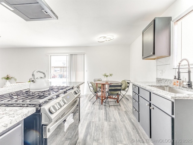 kitchen with gray cabinets, stainless steel range with gas stovetop, light wood-style floors, and a sink