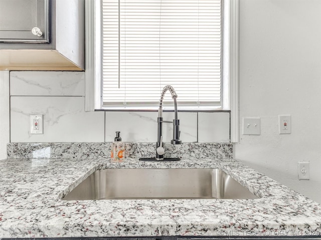room details featuring light stone countertops and a sink