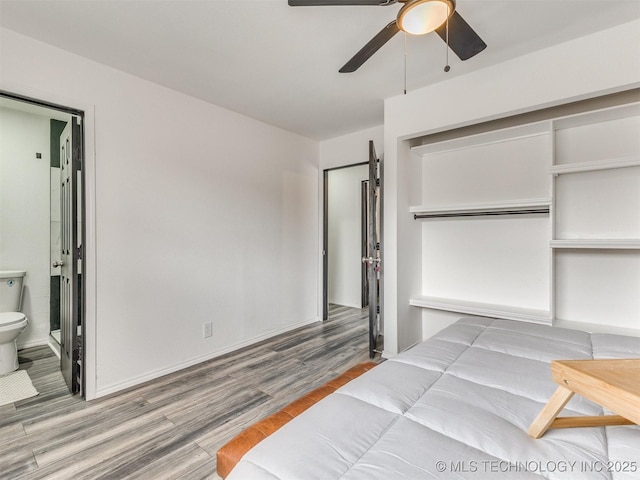 bedroom featuring a closet, connected bathroom, a ceiling fan, and wood finished floors