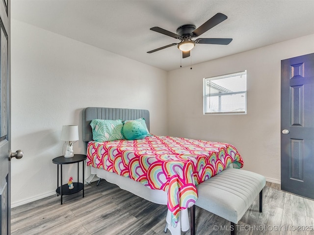 bedroom featuring ceiling fan, baseboards, and wood finished floors