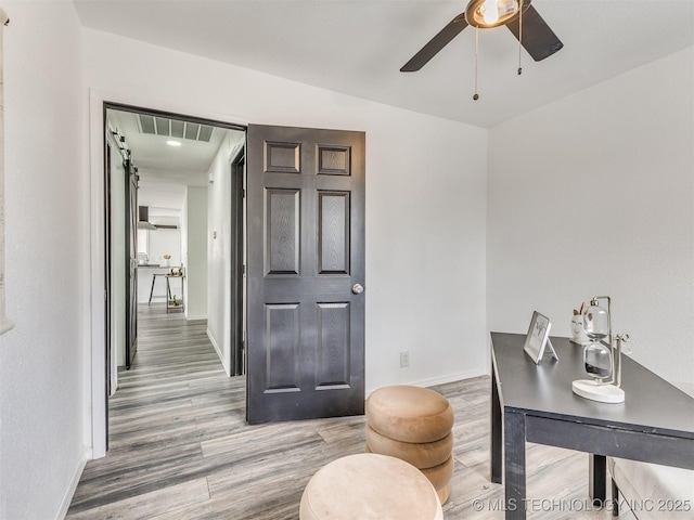 office featuring wood finished floors, a ceiling fan, baseboards, and visible vents