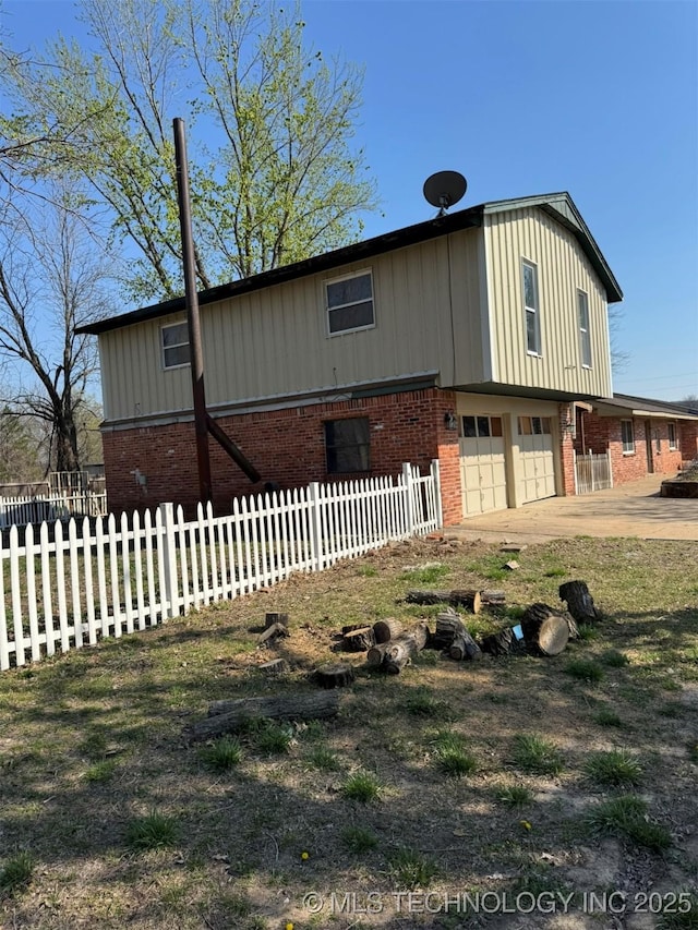 view of front of property with brick siding, an attached garage, and fence