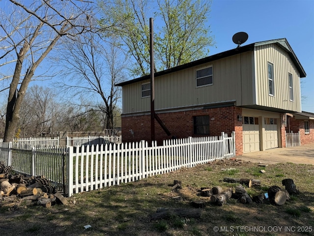 view of front of house with brick siding, concrete driveway, a garage, and a fenced front yard
