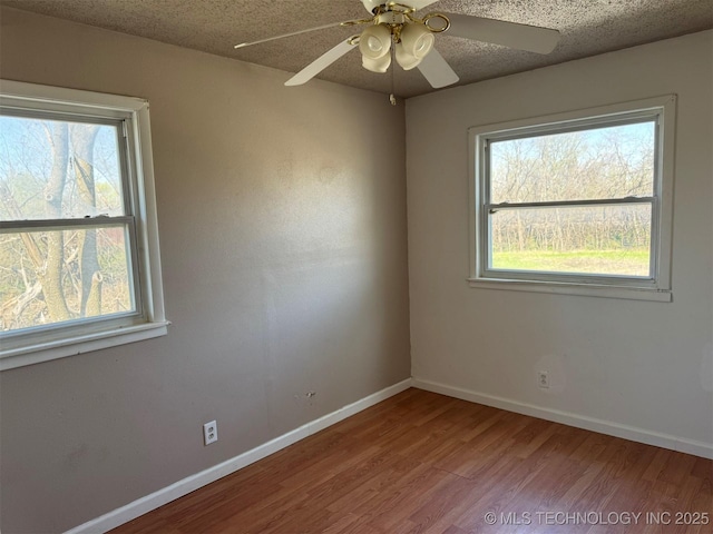 spare room with a textured ceiling, wood finished floors, and a healthy amount of sunlight