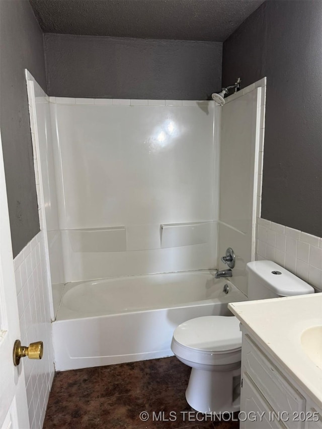 full bathroom with toilet, a textured ceiling, vanity, and shower / bathing tub combination