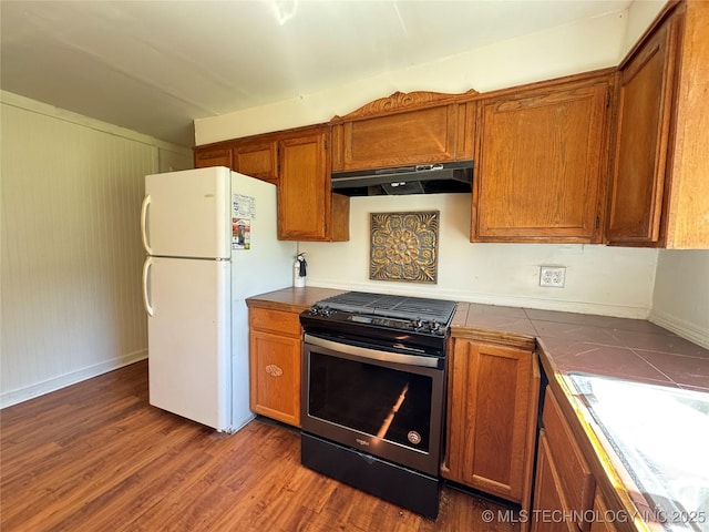 111 N Logan Dr, Tahlequah, OK 74464 - kitchen with gas stove, under cabinet range hood, freestanding refrigerator, and brown cabinets