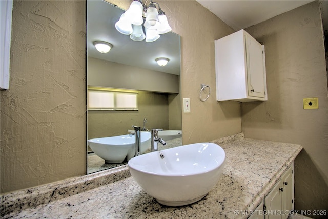 6508 W Cameron St, Sand Springs, OK 74127 - bathroom featuring a soaking tub, a notable chandelier, vanity, and a textured wall